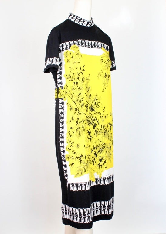 Dress presented by Mr. Dino in black, yellow and white features stand up collar, short sleeves with yellow floral motif color blocking and white fringe border trim at collar, sleeves and hem. Invisible back zip with double hook & eye closure. Mr.