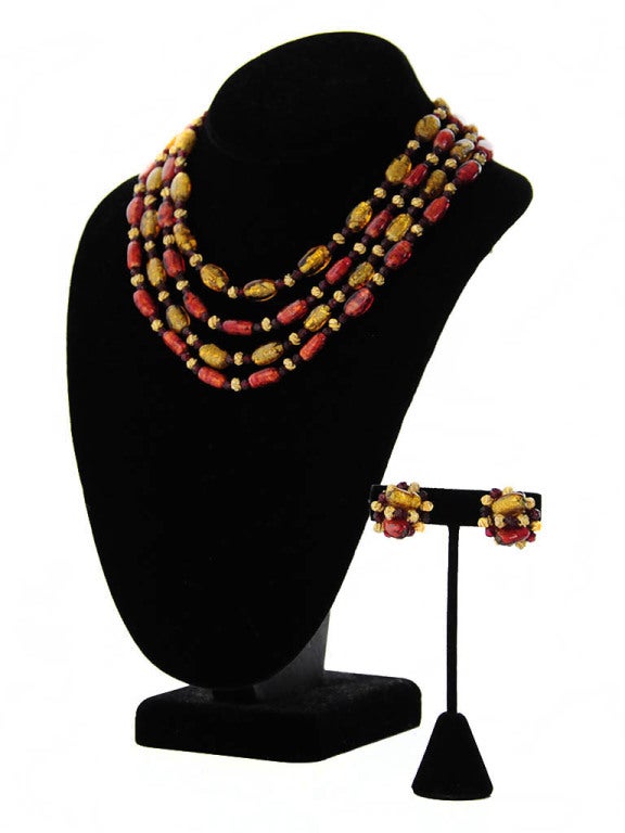 Vintage Hattie Carnegie signed multi-strand necklace and clip-on earring set. Unique abstract amber and garnet colored glass beads spaced with small black and gold beads. The strands are connected to a gold tone bar closure with hook and adjustable