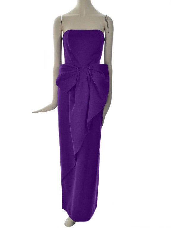 Vintage Victor Costa Sakowitz strapless evening gown in violet satin. Gown features fitted bodice with boning structure, large asymmetric bow at waist, back slit and center back lapped zipper with hook and eye closure. Bodice is fully lined.