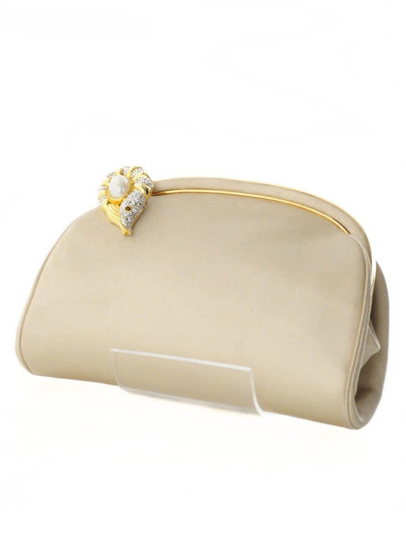 1980's Judith Leiber light gold satin clutch with mother of pearl and swarovski shrimp closure. Optional shoulder strap measures 20'' in length. 

Also inside the handbag are a small gold comb, mirror, and change purse.