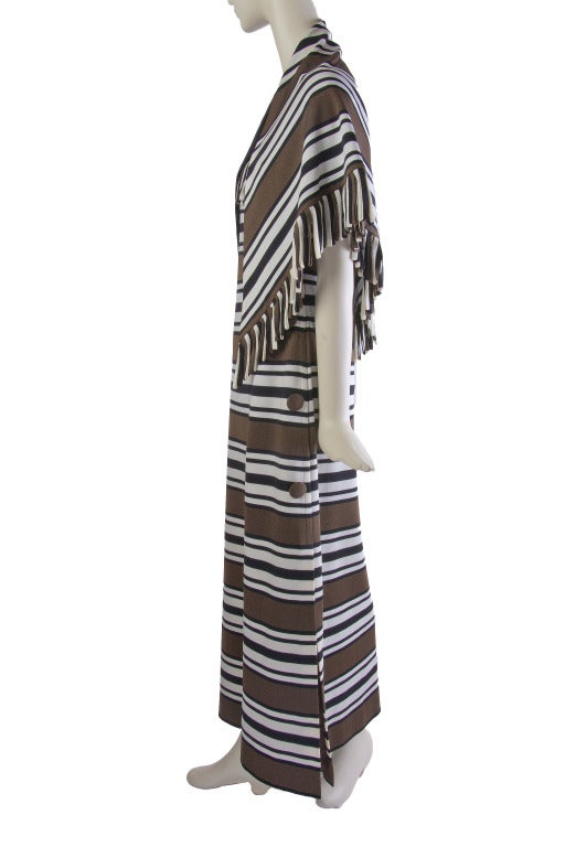 This long brown, creme and white striped dress by Pierre Balmain features thick spaghetti straps, fringe around the bust line, decorative buttons and a matching fringed scarf/shawl.  It has a side zip closure, fully lined and features a leg slit.
