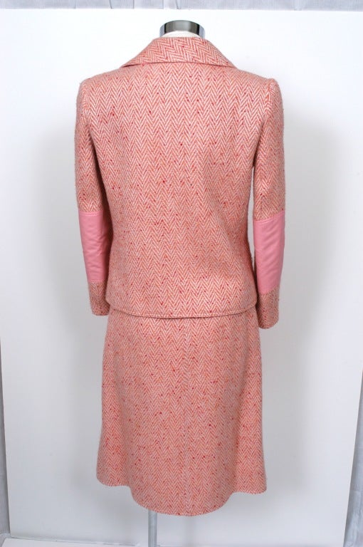 Presented here is a Skirt suit  by Courreges in rose pink wool tweed with double-breasted jacket with six button closure, double notch collar and matching eight button closure a-line skirt. This suit features cotton detailing on lapels, elbow