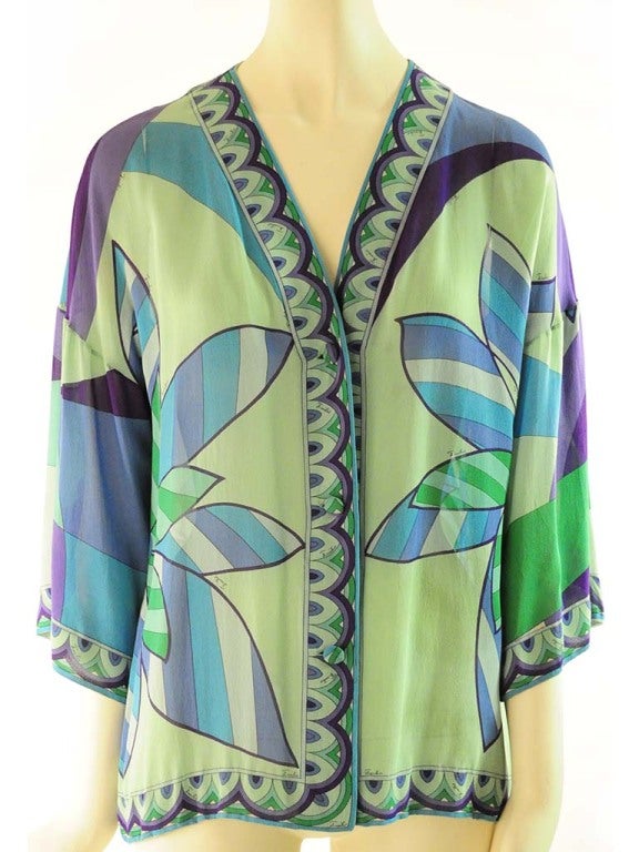 Blouse presented by Emilio Pucci in pale green and teal silk chiffon with intense shades of green and purple. Blouse features a v-neckline, three covered button hole front closure, beautiful border neckline, sleeve and hem and underarm gusset.  The