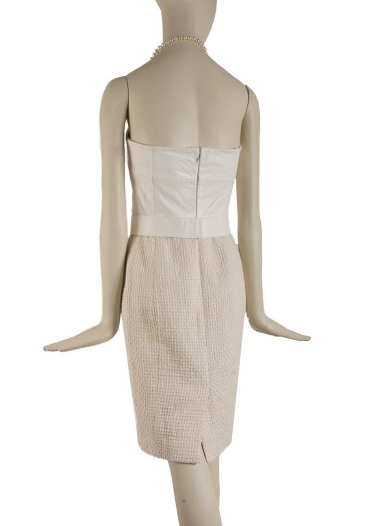 This Chanel dress is presented in creme color with a cotton skirt and a leather halter top.  The halter strap is a strand of pearls.  Two front pockets with pearl & gold tone CC logo buttons adorn the front.  Has zip up the back with an eye hook