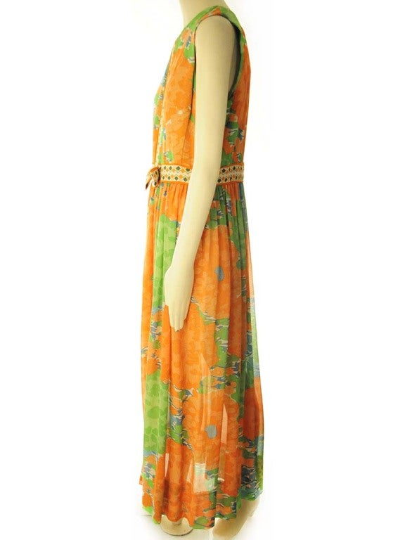 Dress presented by Lilly Pulitzer in cream mousseline silk with large orange and green flowers with teal detail print. Dress features woven ribbon detailing down center front and waist with bow. Dress is fully lined with center back lapped zipper