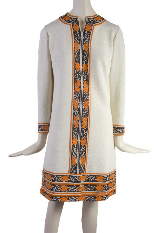 This 1970's vintage dress from Mr. Dino is presented in creme color with a trim of orange and brown floral motif.  It has a zip up the back with an eye hook and features a v-neck.