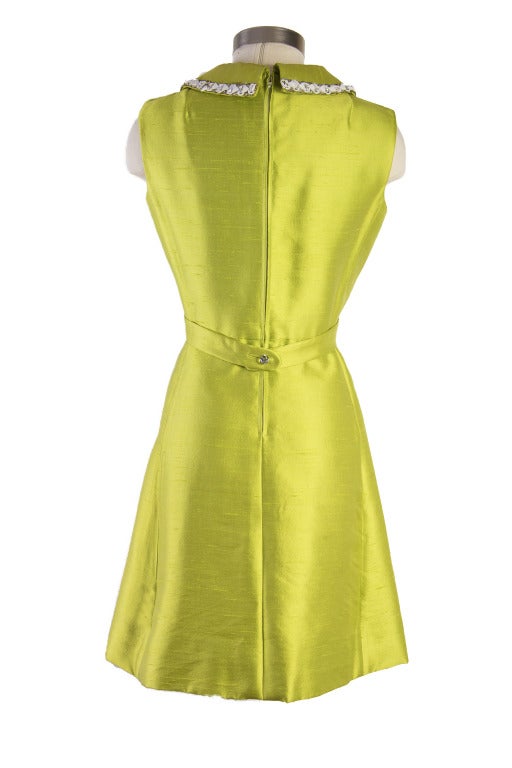 This dress is presented in lime green and is sleeveless with a white beaded collar trim.  It also features a jacket clip that buttons across the back of the dress.  The dress has a zipper and eye hook closure up the back.  The Jacket is long sleeve