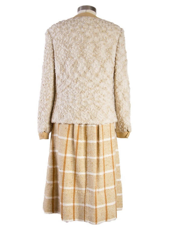 Presented here is a rare two piece suit from Courreges. The set is from the 1960's and is comprised of This two piece set features a boucle top with button closure, banded sleeves and two front pockets.  The plaid skirt is pleated with two pockets,