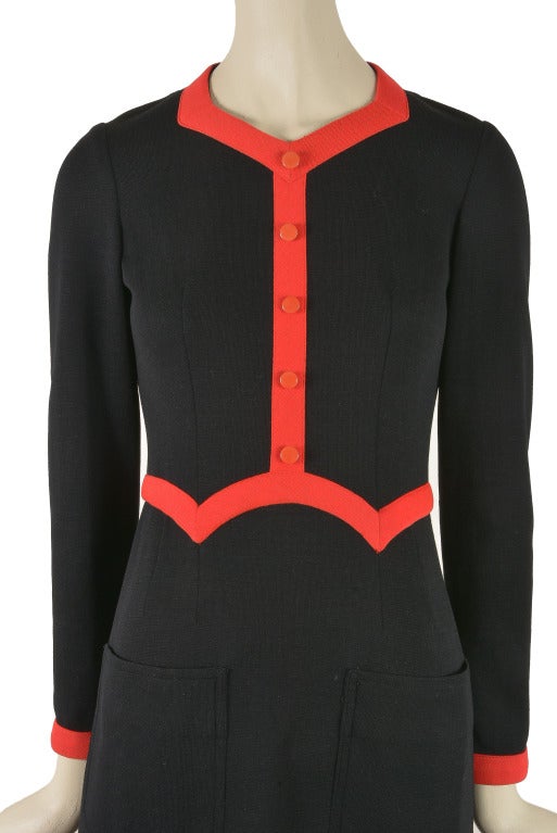 This rare vintage dress by Oscar de la Renta is presented in black with red trim.  It features red mock button front and a zip closure up the back.  Two patch pockets adorn the front as well.  This dress is a rare find!