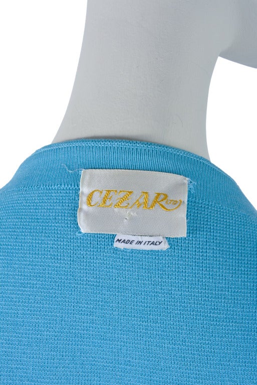 This coat by Cezar is presented in aqua blue and features a knotted flower snap front closure, two front pleated pockets and short sleeves.  This gorgeous vintage coat was made in Italy