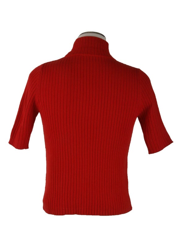 This 1970's vintage sweater is presented in bright reg ribbed knit.  It features a mock turtleneck and short sleeves.  It also has a Courreges logo on the center chest area.