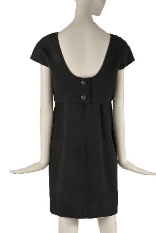 This basic black dress is a marked size 8 and features, cap sleeves, shoulder pads, an open back,  a hidden back zip up button combination closure and is lined.  The dress looks like a top and skirt but it is actually one piece.