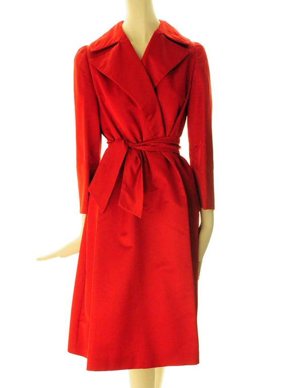 Red silk trapeze wrap coat presented by Pauline Trigere features notched collar; detachable belt and two deep on seam side pockets.
Lined. Measurements:
Shoulder-4 3/4