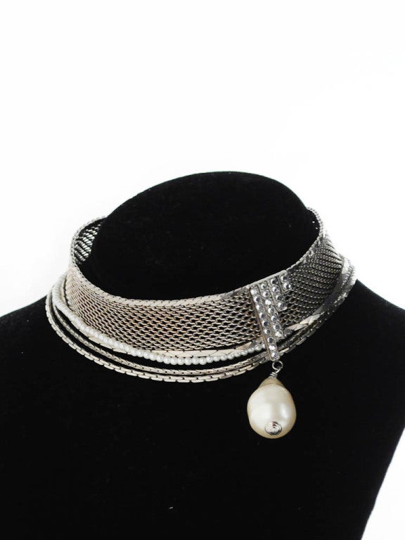 Vintage Chanel choker necklace with three multi-width silver strands and one pearl accent strand. Necklace features an art deco style rhinestone embellishment with large pearl dangle. 

Measurements-

Length: 12-15