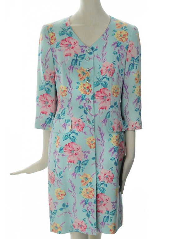 Vintage Escada evening jacket in teal silk with pink, yellow and purple floral print. Jacket features v-neckline, seven front crystal button closure, three quarter sleeves with vent, two hip flap pockets, and shoulder pads. Jacket is fully