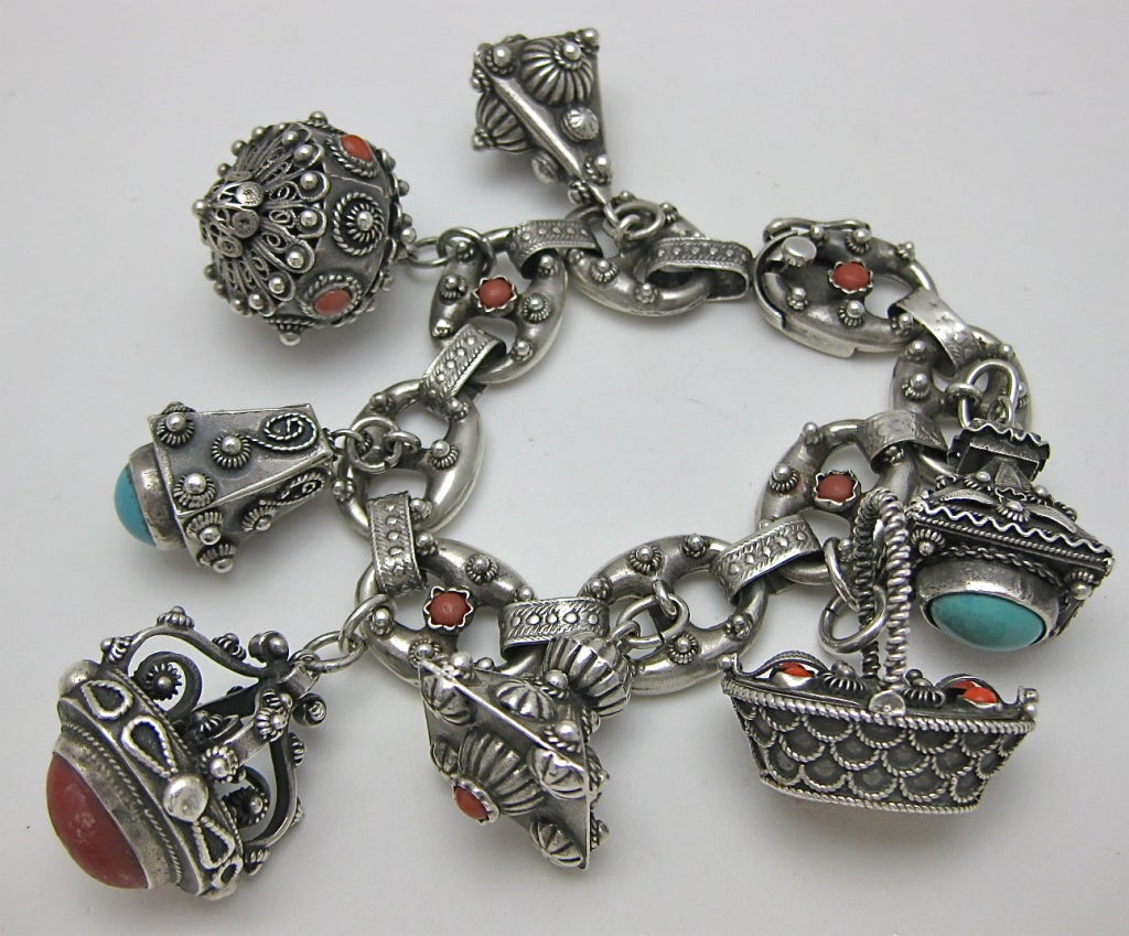 Early 20th Century 800 silver Etruscan revival charm bracelet with seven different charms, two of these have hinged lids to open, the bracelet closes with a safety clasp and it is marked 