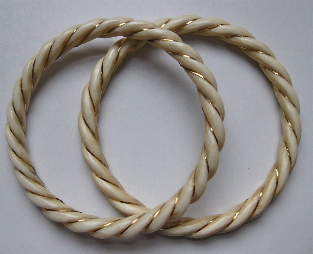 These are two Estate Ivory Bracelets of scrolling design and wrapped in between spaces with a yellow gold wire. They are not exactly the same size, one is 8 cms of circumference and the other is 7.6 cms as well but the difference is not perceptible
