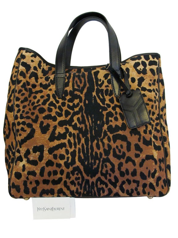 Hello kitty! Striking YSL leopard print canvas tote with black leather handles and black trim and piping. Spacious light khaki colored interior with one side pocket and one small phone pocket; single gold-tone snap closure and 6