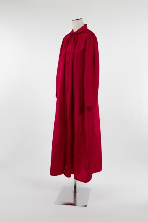 Luscious raspberry taffeta evening coat with Peter Pan collar and ten covered buttons down the front. The coat is gathered at the back neck and at both sides of the front placket; unlined. Smocking at shoulders.

Photography provided by Drew