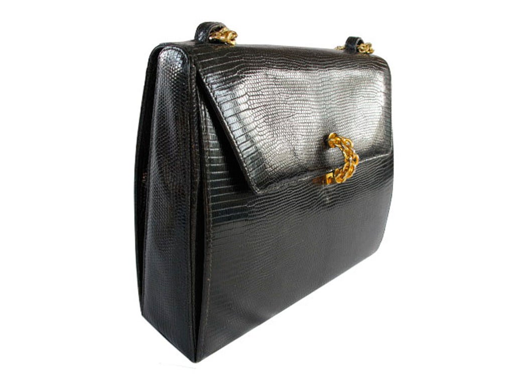 Elegant day handbag by Paloma Picasso in lizard from Italy. Hallmark in lettering: Paloma Picasso. This purse features a chain link semi-circular shaped front clasp, gold chain link shoulder strap, nine gold conical studs at bottom of purse, one