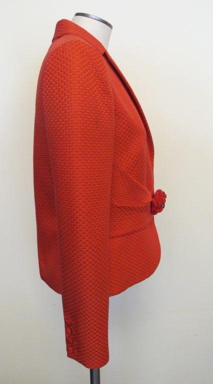Stand out in a crowd in this stunning silk blend red-orange basket weave jacket. Notched collar with two artfully sewn horizontal pleats at bodice with whimsical red jewel embellished rosette fastening at waist; sleeves terminating in four