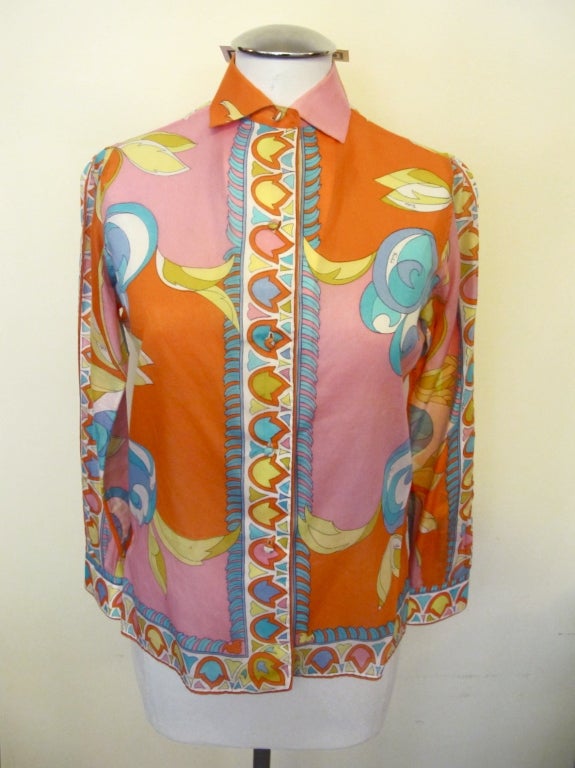 Colorful patterned blouse enhanced by bright orange, turquoise, light shocking pink and shades of yellow. Fabric covered buttons up the center and at sleeve cuffs. Marked size 8, will fit modern size 4. Measures 15.5" from shoulder to shoulder