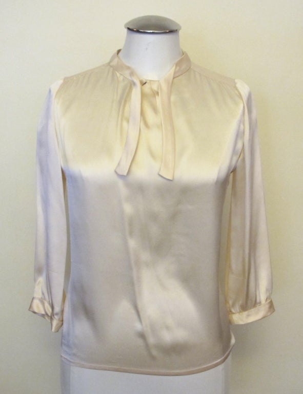 Elegant, chic 1967 creamy white silk blouse from collection of Grande Dame with continuous fabric forming silk ties on neck. Blouse measures 13.5 inches from shoulder to shoulder and has 17.5 inch (three quarter) sleeves.

Photography provided by