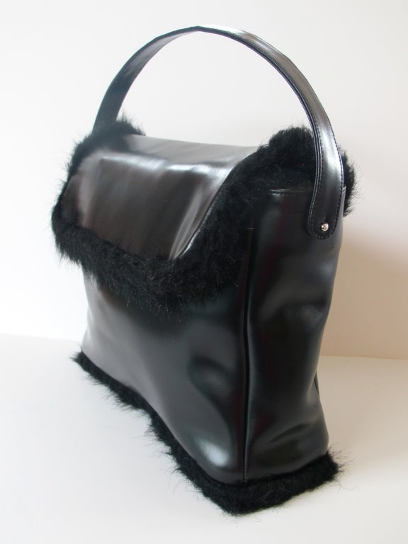 Black leather handbag fully lined with faux fur. Faux fur trim also extends to border flap and bottom frame. 5 inch strap drop.

Photography provided by Roberto Rosas-Mariscal for Helpers House of Couture.