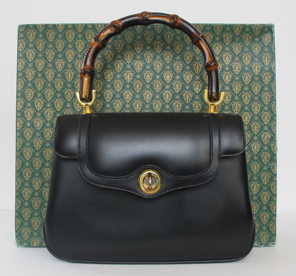 New exquisite Gucci black leather handbag with iconic bamboo handle and gold and silver hardware. Lined in maroon leather and comes with maroon leather coin purse and purse mirror. Original Gucci box and dust bag. Handle measures 12.5 inches