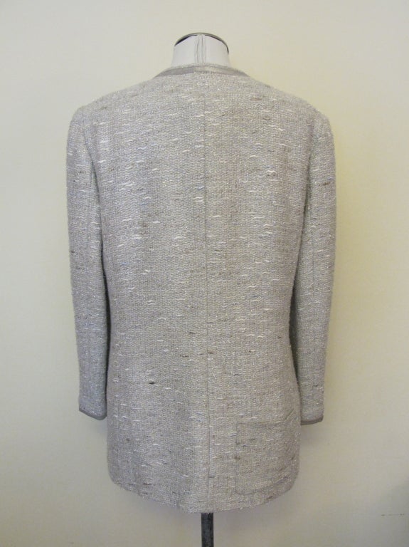 Chanel light silver grey jacket with silver specs. Silver grey leather trim around cuffs and neckline, terminating in center front tie. Two pockets in front and 1 pocket in back. Sleeves measure 22