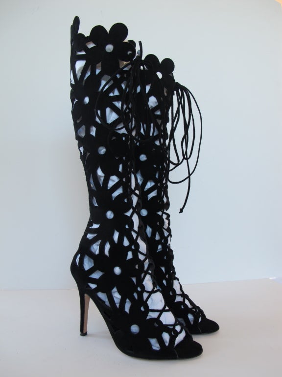 Black laser cut suede lace-up knee boots feature a floral and geometric design. Peep-toe.