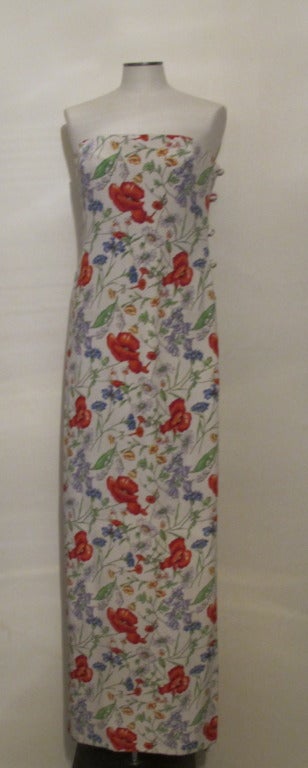 Strapless floral print evening gown by Bill Blass with high slit and nine asian inspired knot closures. Flowers in the print include: poppies, lilly of the valley, sweet peas and daisies. Slit is 31.5 inches from the hem up.