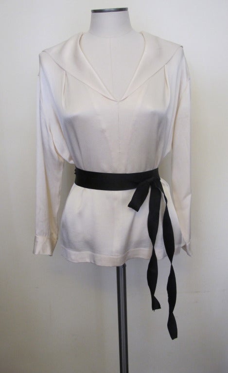 Cream Chanel blouse in a textured silk with a sailor collar; tied at the waist with a black satin ribbon, with 3/4 length sleeves. Sleeve length 19.5 inches, shoulder to shoulder 18 inches