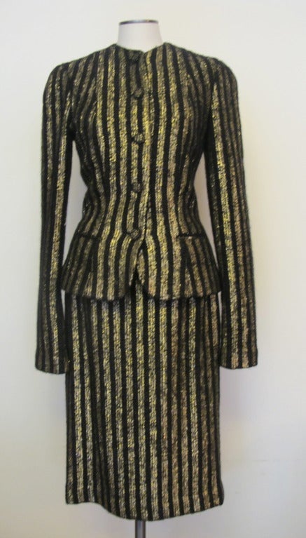 Two piece black wool suit with embellished gold stripes, 5 covered buttons with same fabric. Size 4, Jacket 33 inch bust, waist 28 inches, hips 36 inches, Skirt length is 28 inches, Jacket length is 23 inches, Jacket sleeve length is 28 inches,
