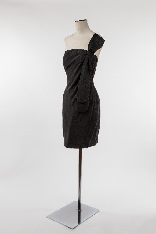 A dramatic silk strapless dress, fabric of a sexy reptilian-like texture with side zipper and asymmetrical tie embellishment; fully lined with top boning provide to provide the perfect structure. Anouska Hempel has designed couture clothes for