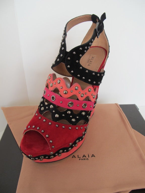 Description: Fabulous, chic, iconic, watermelon and cranberry suede platform wedges with graphite silver-tone studs and eyelet accents. Straps around foot are in colors of black, shocking pink and rose pink. Wedge heel measures 6 inches high. Size