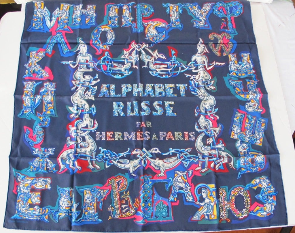 Motif on scarf says: Alphabet Russe par Hermès A Paris. Navy background.
‘Alphabet Russe’ is a design of Evgenia Miroshnichenko, the first Russian contemporary designer to collaborate with Hermes.