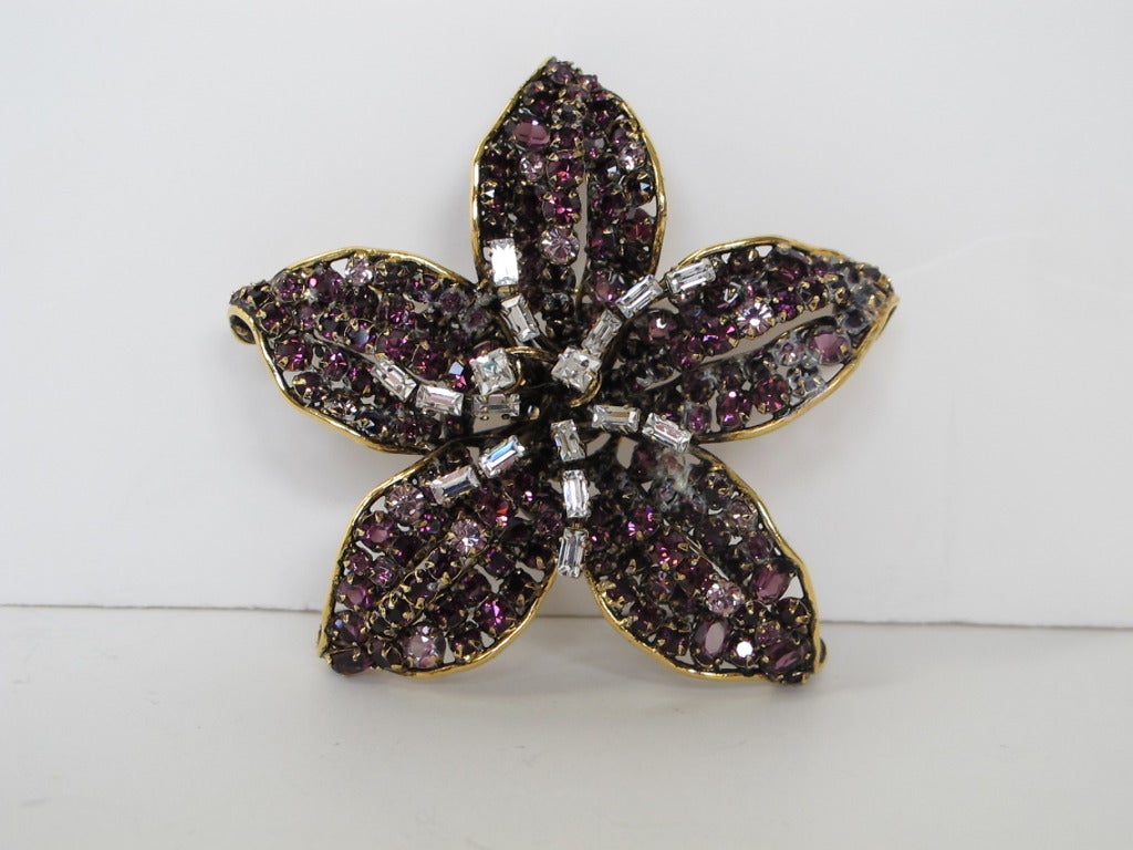 Statement flower pin encrusted with purple rhinestones and rhinestone baguettes. The piece is fabulous and the stones are perfectly set, signed by the designer. Five petals form the piece.