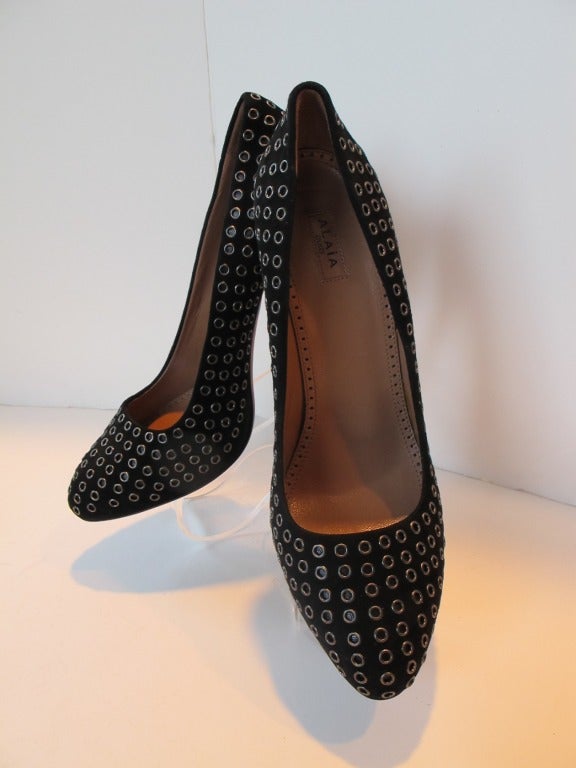 Azzedine Alaia classic black suede eyelet pump. Underneath the eyelet lies a bedding of black leather.  Comes with original Alaia box with Saks Fifth Avenue label on brown box. Inside of heel measures 3.5 inches. Outside of heel measures 5.25