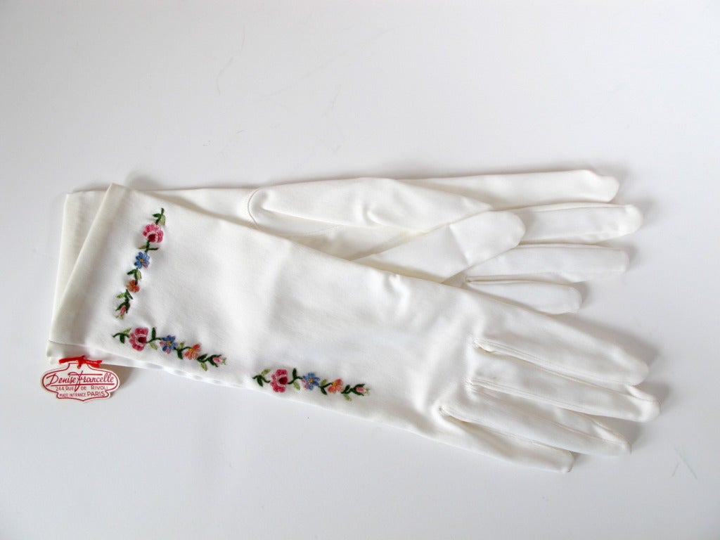 Elegant white stretch gloves with forget-me-not and baby rose hand embroidery.
Label inside of glove and paper label outside of glove says:
Denise Francelle
244, Rue de Rivoli
Made in France Paris