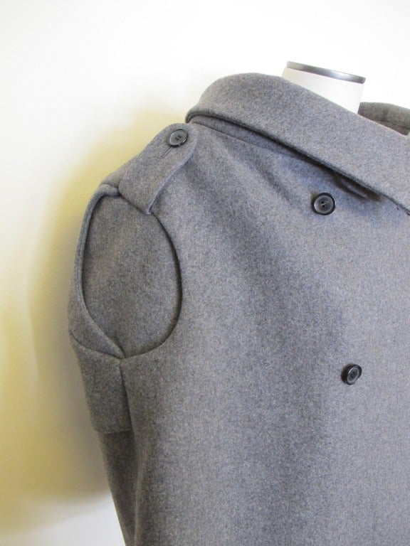 Innovative iconic Alexander McQueen grey jacket. Back of jacket is a cape with black leather triangle. Stunning - show stopper - when worn. Shoulder to shoulder measures 19.5 inches.