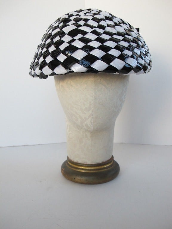 Chic Black and White checkered shiny straw hat with large black patent leather bow in back of hat. Hat should be worn tilted on the forehead, over the eyebrows.