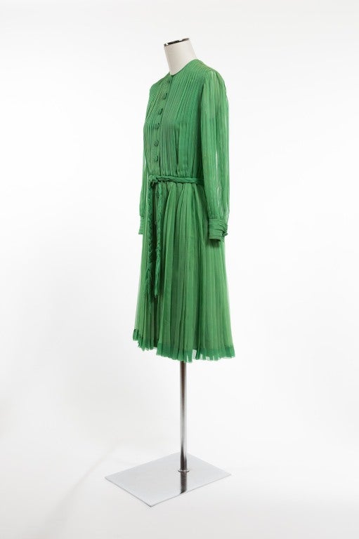 A jade green goddess creation! Finely pleated throughout with nine silk chiffon covered buttons featured on center front of dress; upper torso with vertical pleating; pleated long sleeves terminating in artfully detailed horizontally pleated cuffs