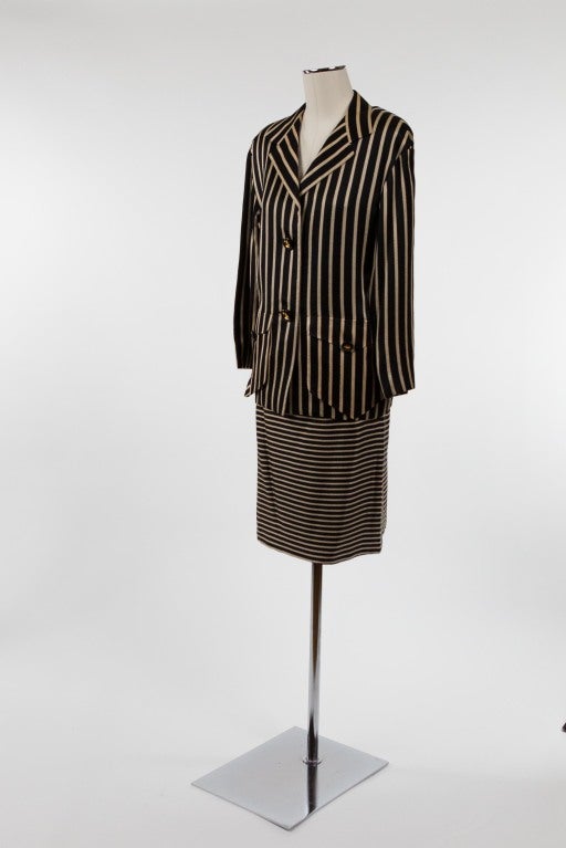 A super-chic silk skirt and jacket that is a study in Galanos style and craftsmanship. The vertically striped single breasted jacket in black and cafe au lait with notched lapel and shoulder pads; two black and gold buttons secure the front of the