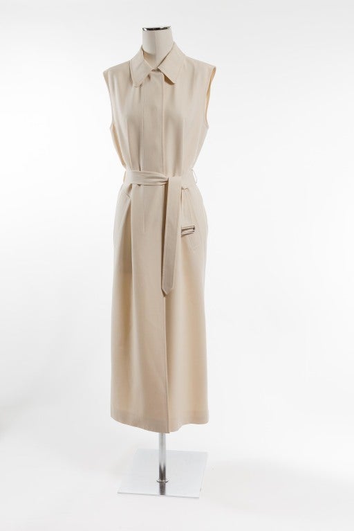 A sleeveless cream-colored gabardine virgin wool coat dress with hidden front buttons and deep diagonal side pockets; matching 1.75