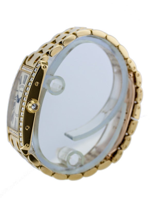 Lady's Cartier Tank Americaine in 18k yellow gold, on 18k yellow gold bracelet, and concealed folding clasp. Diamond bezel, diamond faceted crown. Case dimensions, 35mm (including lugs) x 19mm. Quartz movement. Ivory-colored dial with painted Roman