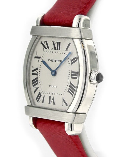 Lady's Cartier platinum tonneau wristwatch on original satin strap and 18k white gold deployant buckle, sapphire cabachon crown, case diameter 34mm x 26mm, manual-wind movement, silvered guilloche dial with Roman numerals and blued hands, box.