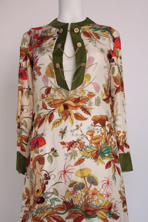 This is a 100% silk Gucci tunic dress in the Accornero pattern - a design by Gucci illustrator Vittoria Accornero. Lined in silk. The background is off white with olive green silk banding the cuffs, hem and neckline. The pattern is rendered in