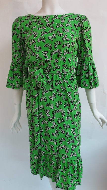 Vintage YSL kelly green silk dress with with pattern of bows and polka dots. With silk tie belt that attaches to the dress. 100% Silk. Size 38. Measurements:
Waist: 16