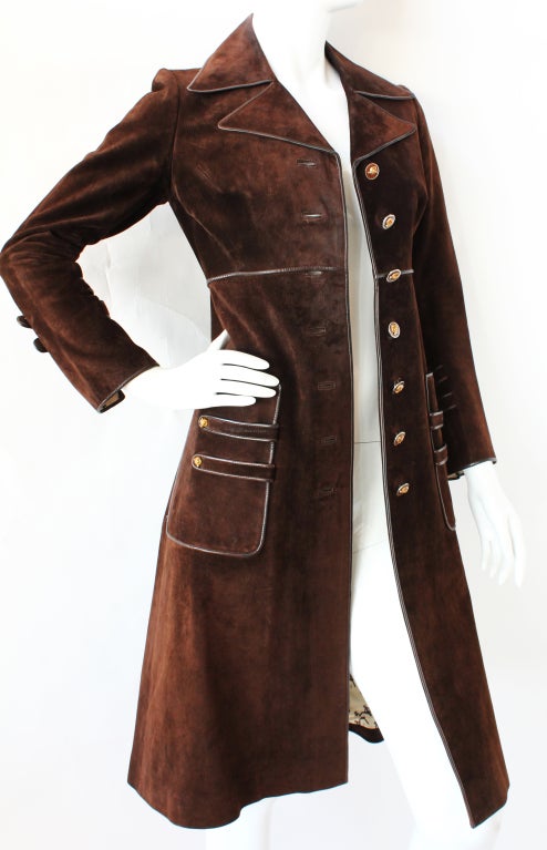 A deep chocolate brown Gucci suede coat from the 1970s that features an outstanding combination of hardware and details: seven enameled fox head buttons, leather piping, patch pockets and notched sleeve both trimmed with twin straps and buttons, a